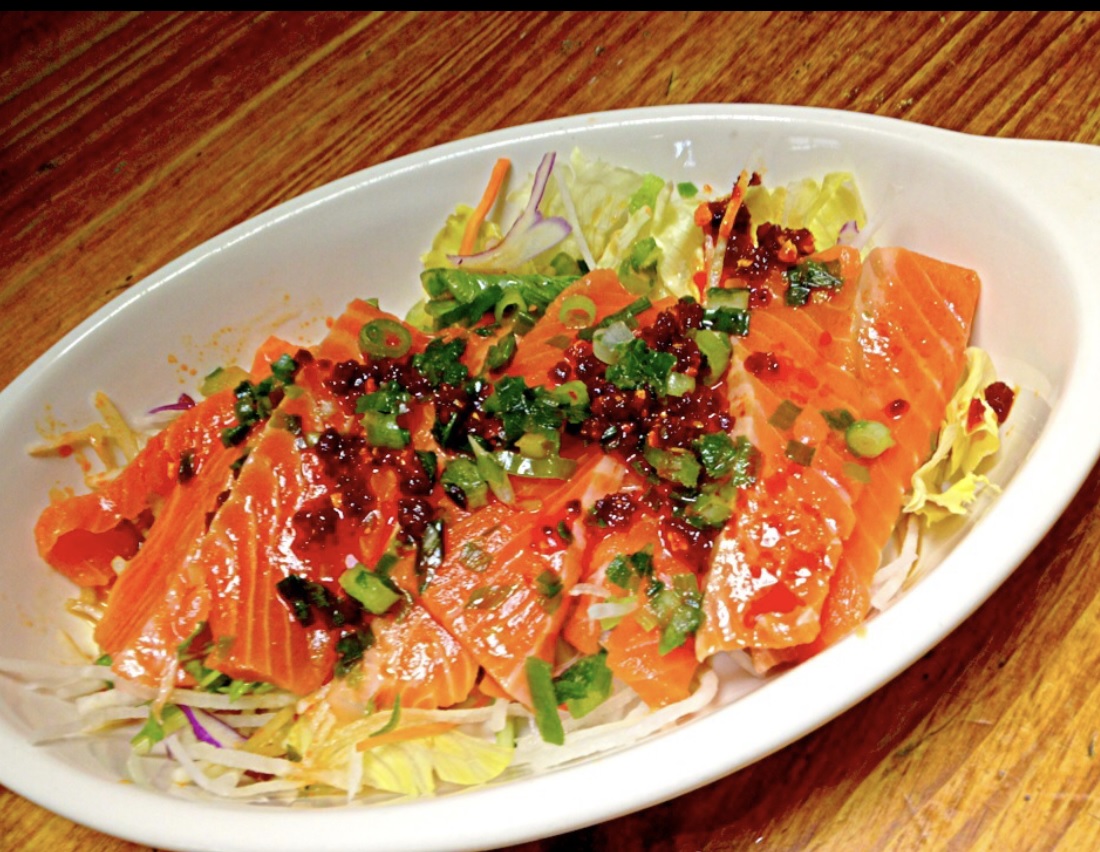 Raw Salmon with hot chili oil on top and shredded cabbage under them.