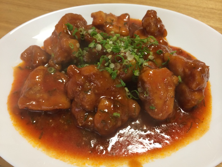 Ketchup based chili sauce on top of deep fried chicken. Sliced green onions on top.