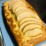 Light brown color whole apple pound cake on a blue plate.