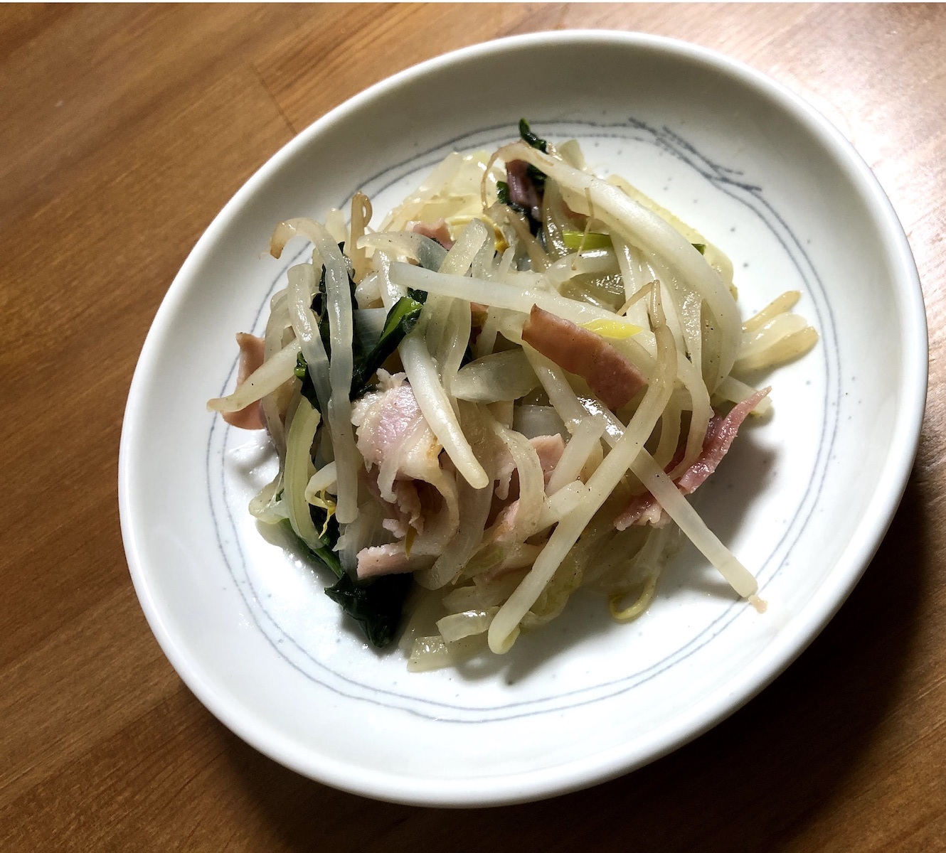 Bacon, bean sprouts, and spinach stir fry on a plate