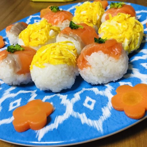 4 pieces of salmon sushi balls and 4 pieces of egg sushi balls on a blue plate.